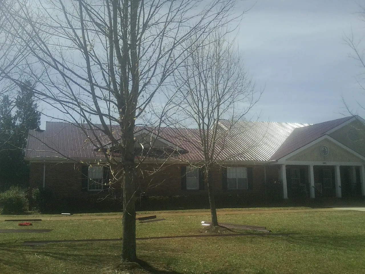 Red metal roof on a brick building seen from the front lawn in Wildwood
