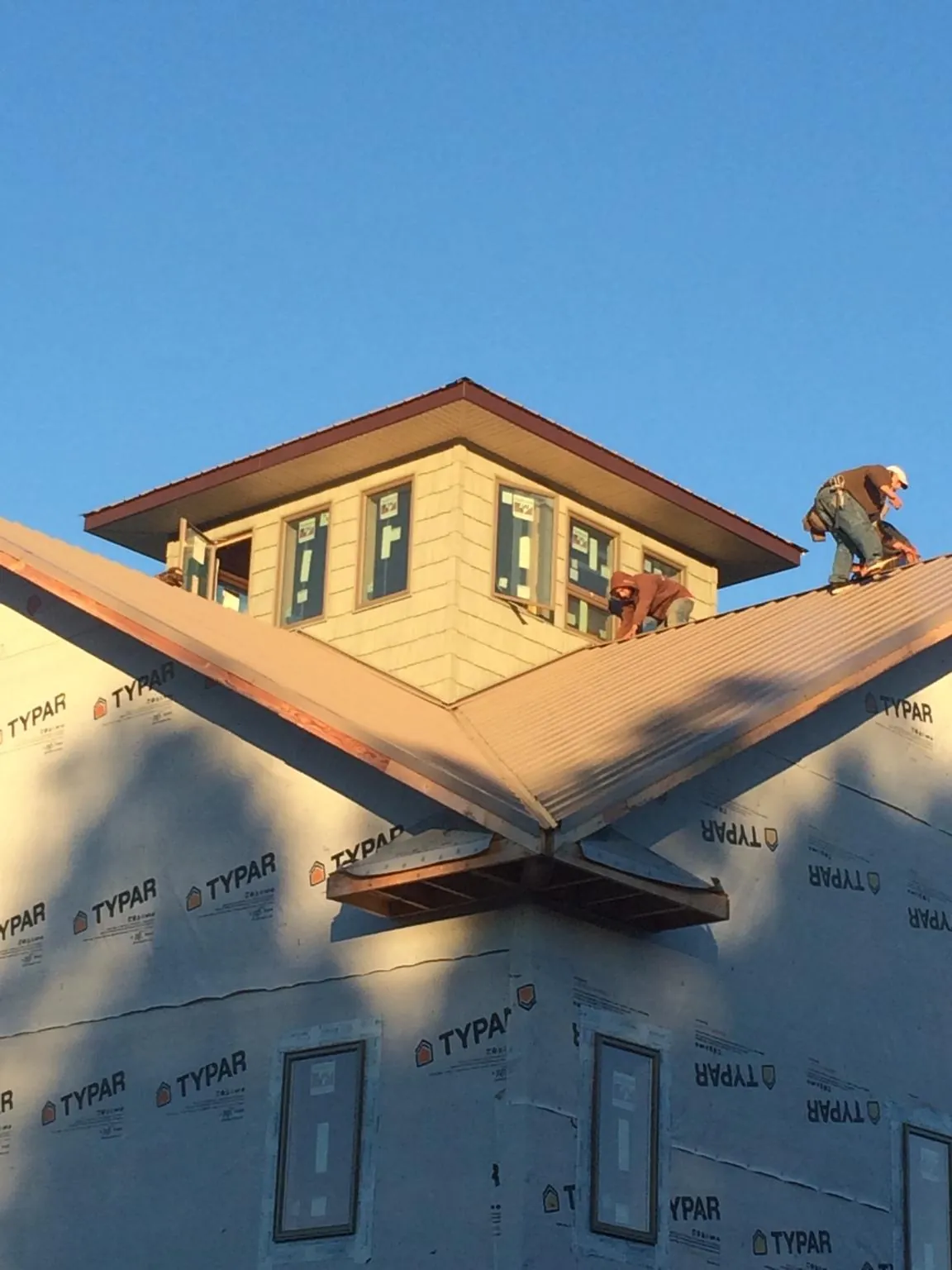 Roofers working around a rooftop cupola on a new metal roof at sunset — Roof Waterproofing in Wildwood by Roofing Brothers